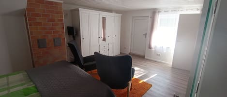 Een slaapkamer met een bed, bureau, stoel, kledingkast en een raam met gordijnen.
