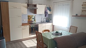 Eine kleine Küche mit Essbereich, ausgestattet mit einem Herd, Spüle und einem Tisch mit Stühlen.