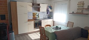 A compact kitchen with a dining area, featuring a stove, sink, and a small table with chairs. - Cozy, modernly furnished vacation rental with a private entrance in an annex (Burgebrach)