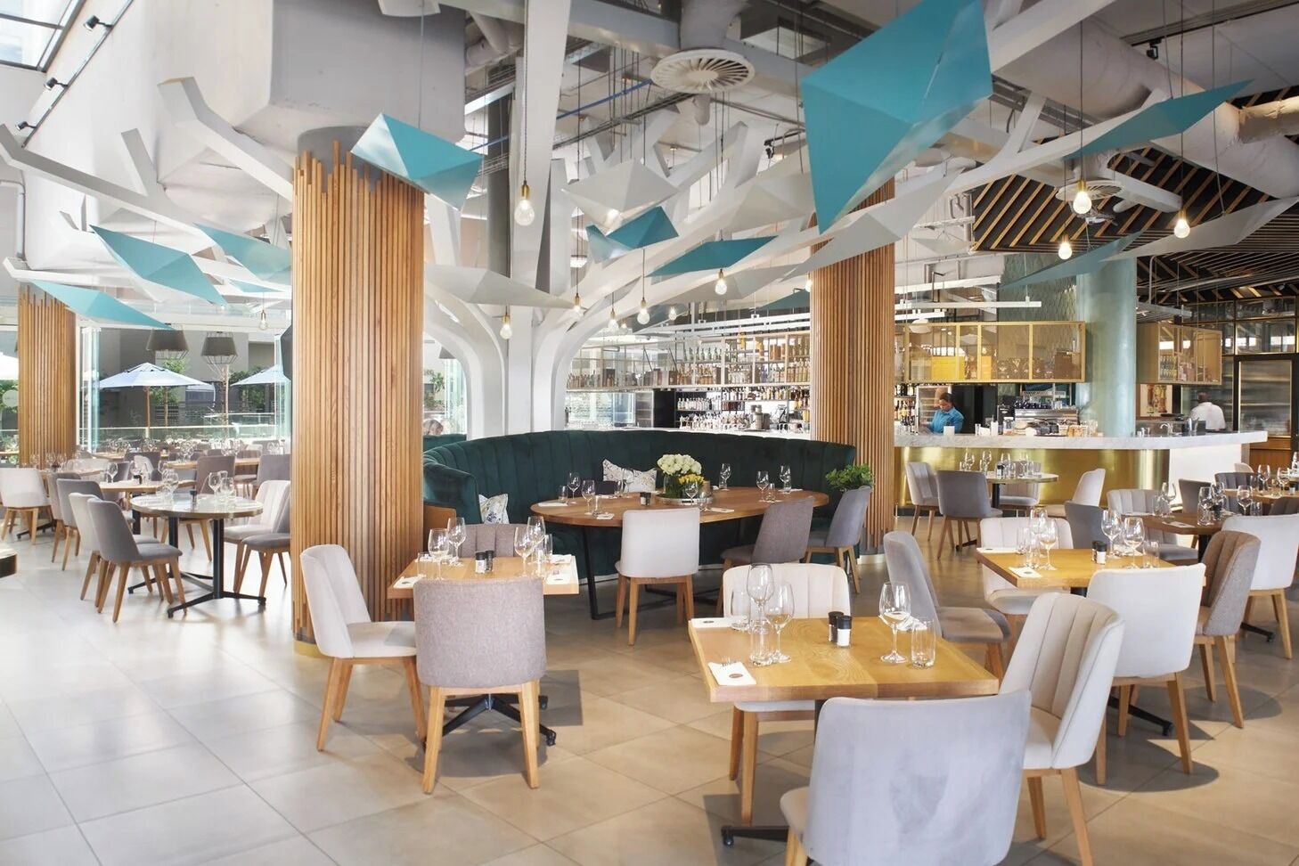 Un restaurante moderno con mesas redondas, sillas y una zona de bar.