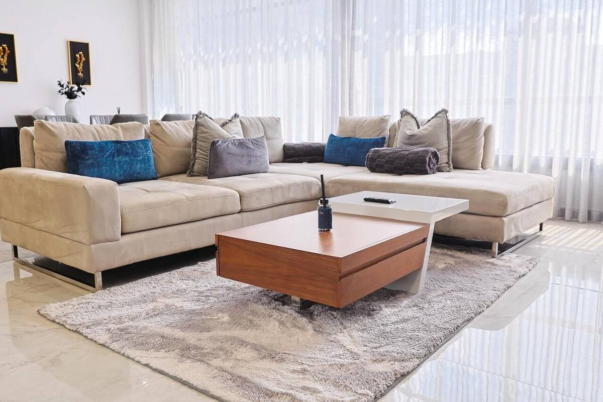 A modern living room with a beige sofa, a wooden coffee table, and a fluffy rug.