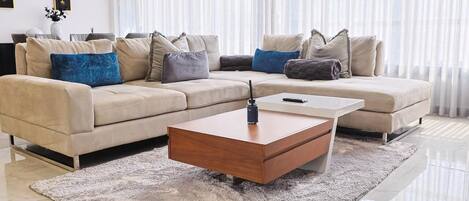 Una sala de estar moderna con un sofá color beige, una mesa de centro de madera y una alfombra mullida.