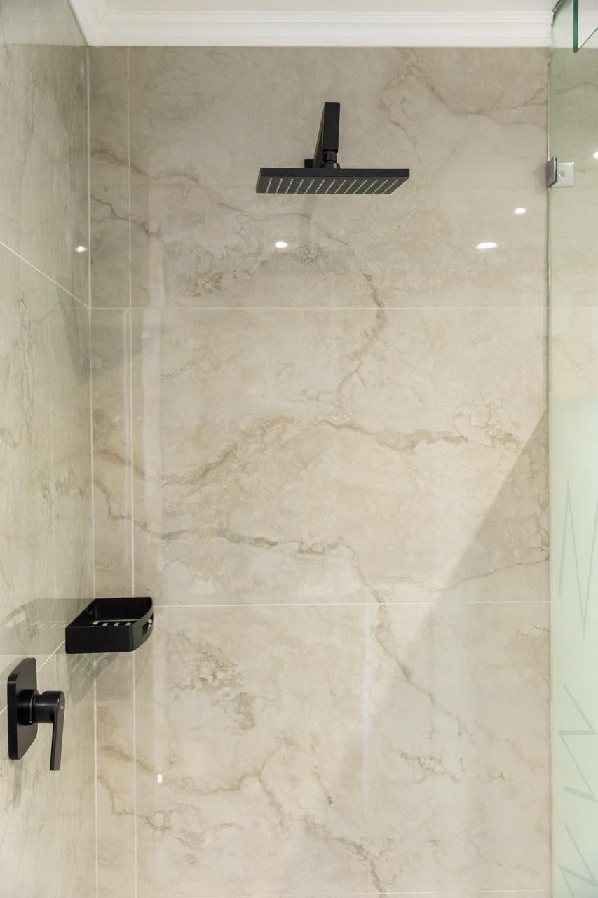 A bathroom with a shower, a toilet, and a glass partition.