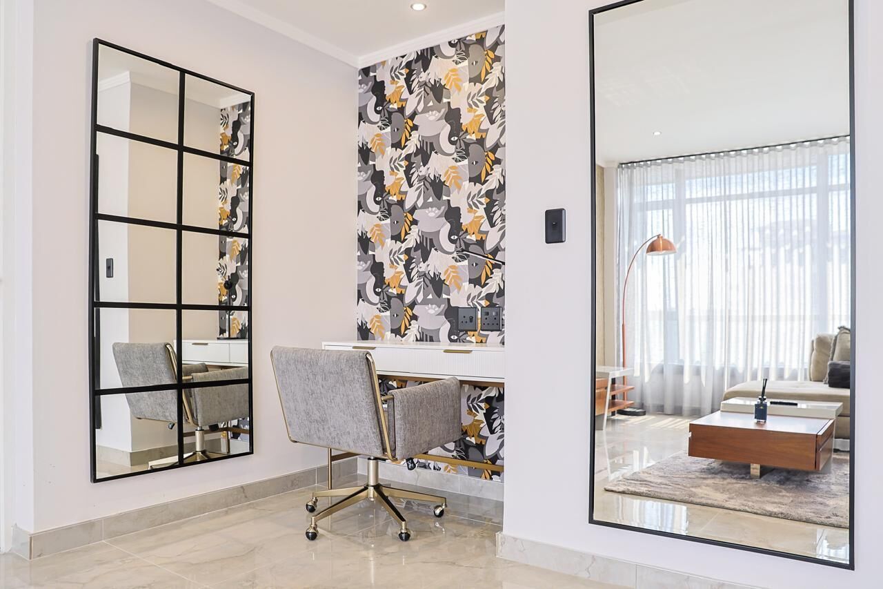Un espace de bureau moderne comprenant un bureau, une chaise et un grand miroir.