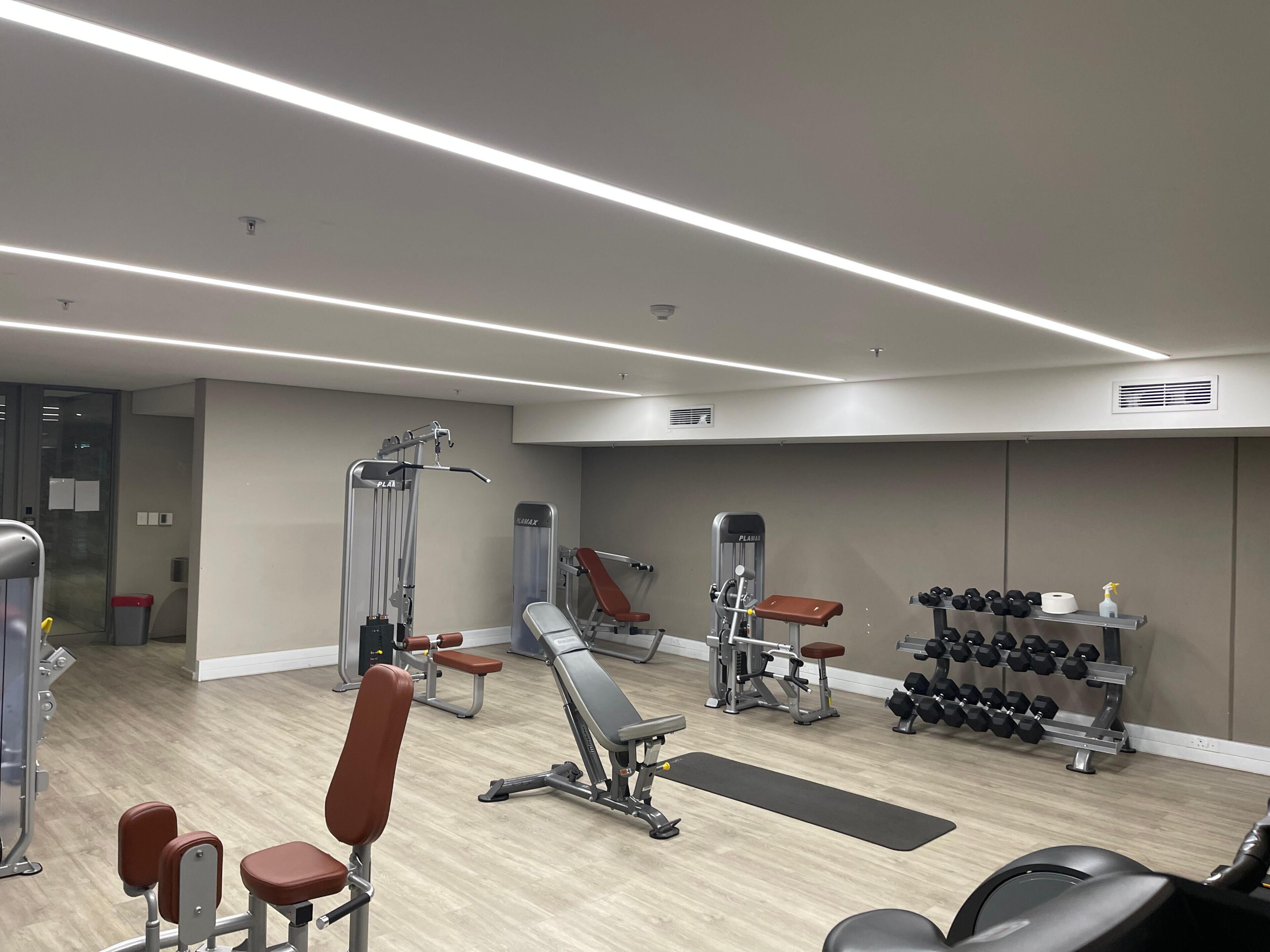 A gym with various exercise equipment, including benches, dumbbells, and weight machines.