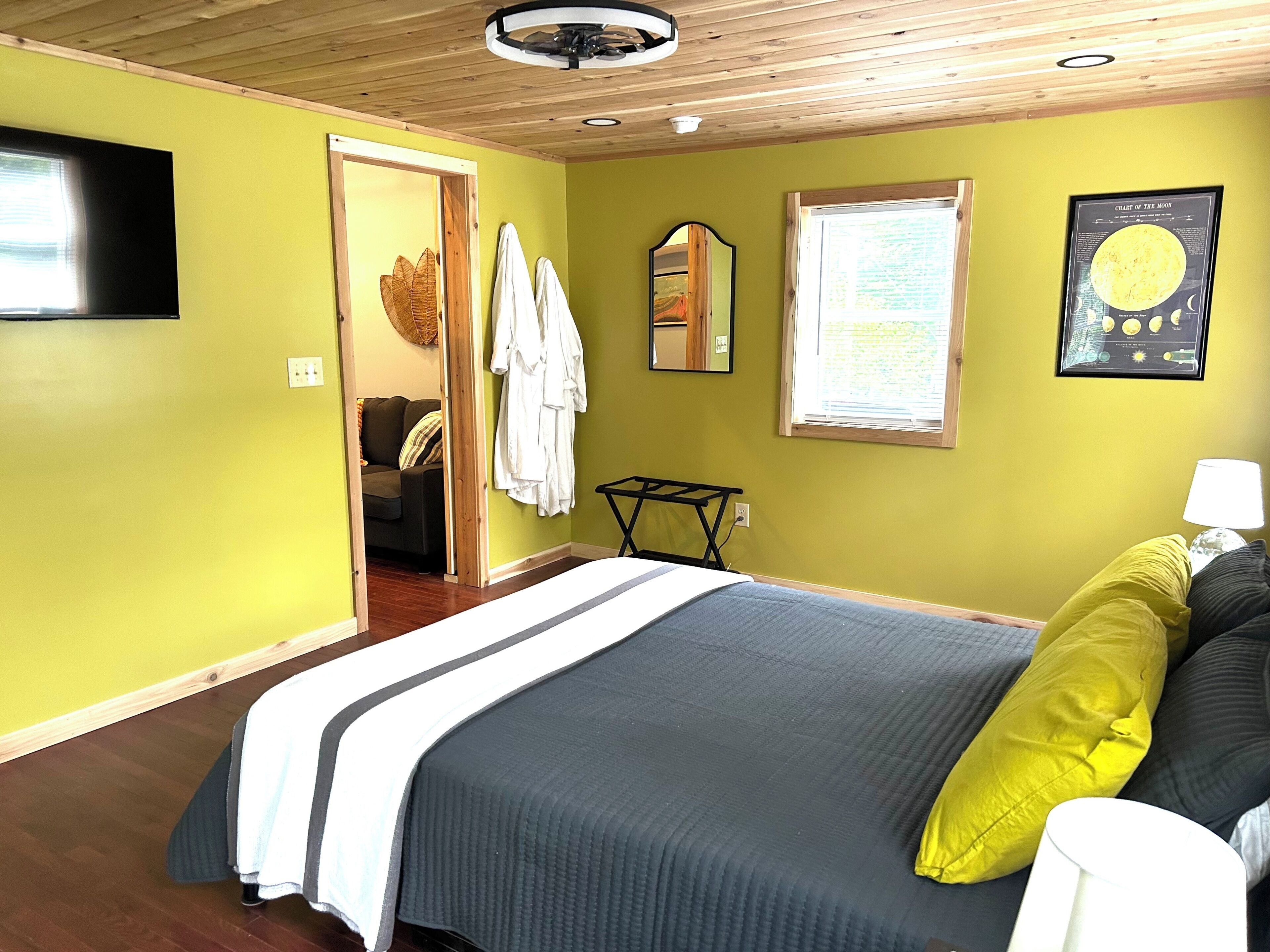 Une chambre à coucher avec un lit, une télévision, une fenêtre et un miroir.