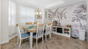 A dining area with a wooden table, white chairs, and a wall mural. - Home from Home in Heritage Landing Golf Community (Punta Gorda)
