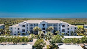 A multi-story hotel with a flat roof, surrounded by palm trees and a clear view of the ocean. - Home from Home in Heritage Landing Golf Community (Punta Gorda)