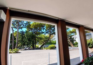 A view through large windows of a parking lot with trees and a building in the background. - Apartment with balcony and parking in La Baule (La Baule-Escoublac)