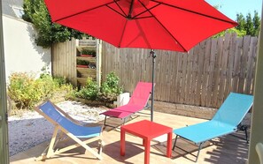 A patio with two lounge chairs, a small table, and a red umbrella. - Charming house with garden in La Turballe (La Turballe)