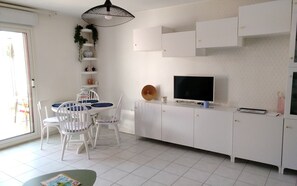 A modern kitchen with white cabinets, a dining table with chairs, and a television. - Charming house with garden in La Turballe (La Turballe)