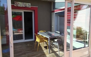 A room with a sliding glass door, a table with chairs, and a view of the outside. - Charming house with garden in La Turballe (La Turballe)