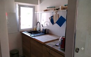 Una cocina pequeña con ventana, un lavamanos, una estufa y una encimera.
