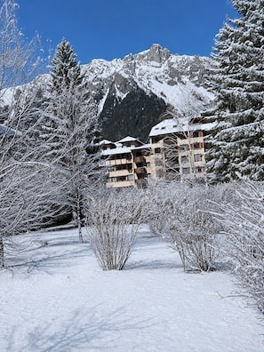 Eine verschneite Berglandschaft mit einem Gebäude, das mehrere Balkone und ein schneebedecktes Dach hat.