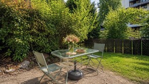An outdoor seating area with a table and chairs, surrounded by greenery and a fence. - Renovated with garden & Mont Blanc view (Chamonix-Mont-Blanc)