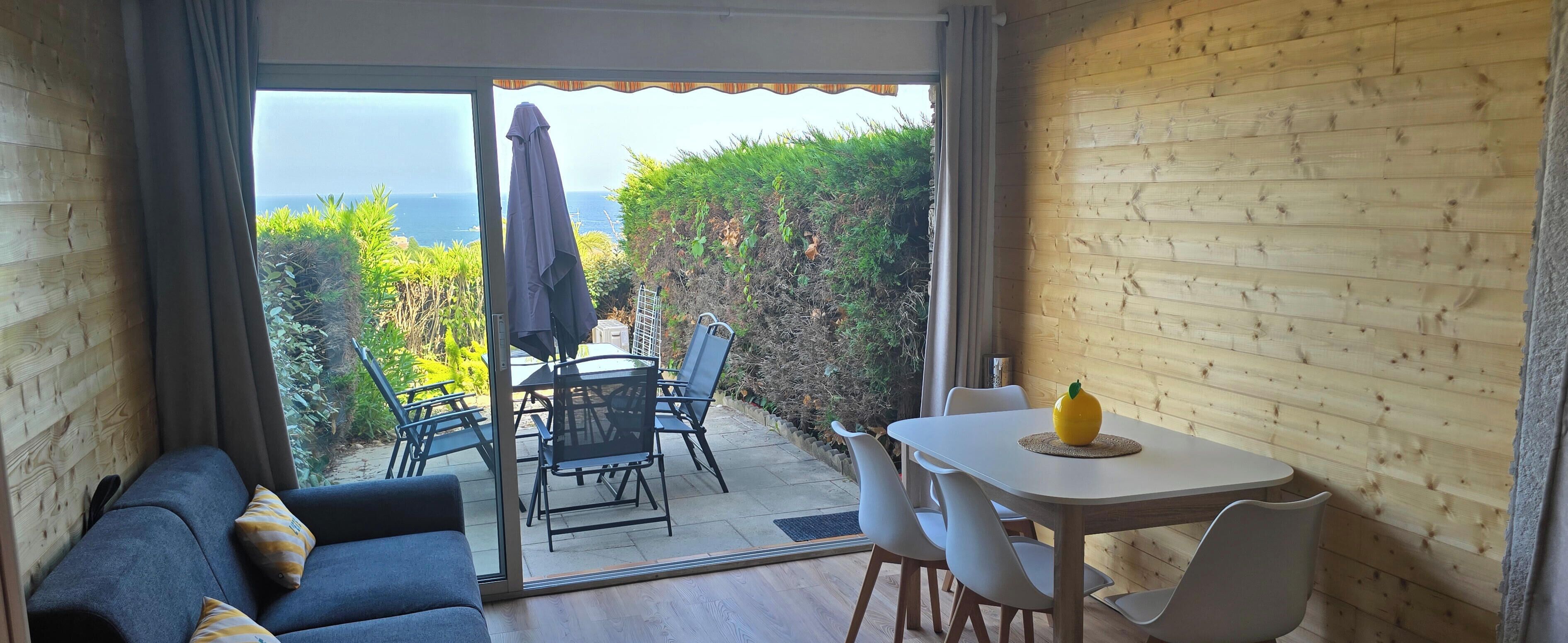 Una habitación con puerta corrediza de vidrio que da a un patio exterior con mesa y sillas.