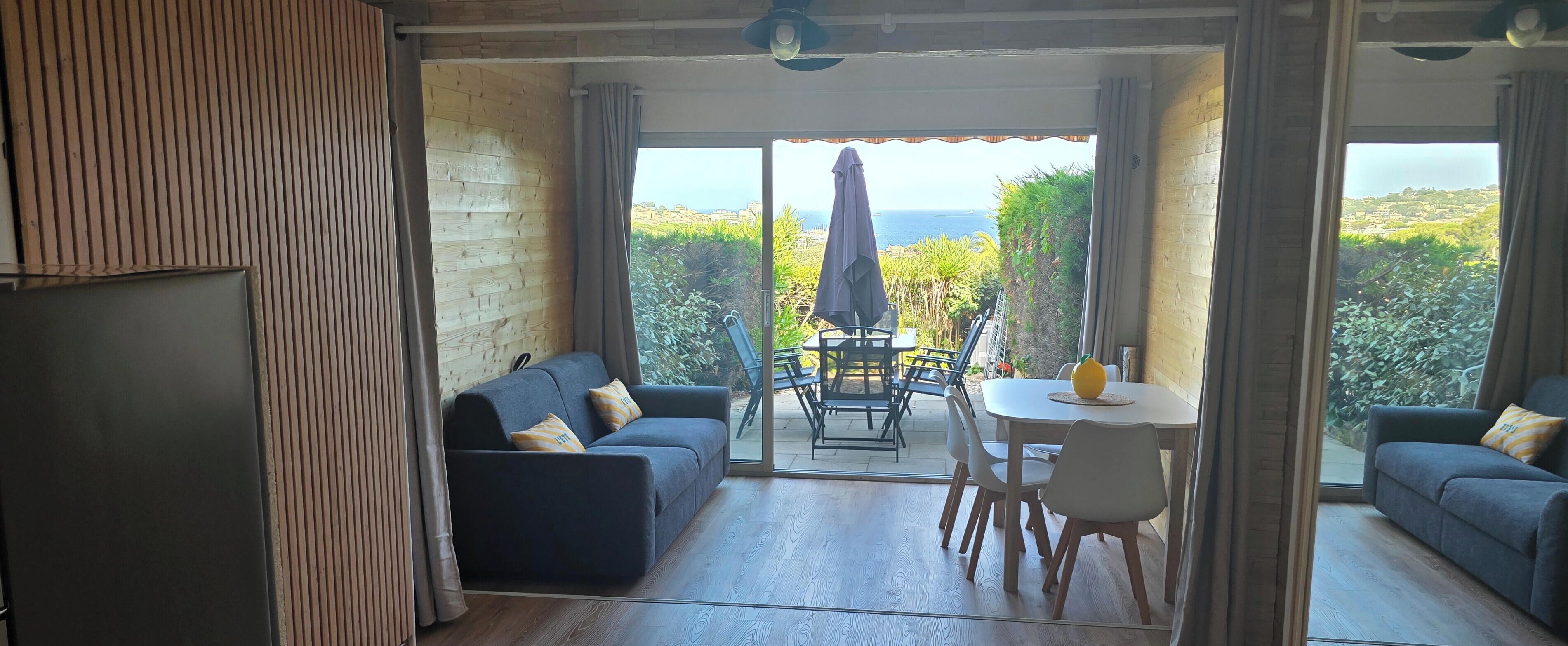A cozy interior with a sofa, a dining table, and chairs, and a view of the outdoors.