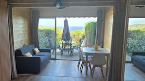 A cozy interior with a sofa, a dining table, and chairs, and a view of the outdoors. - Studio with sea view, terrace and shared pool (Sainte-Maxime)