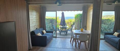 A cozy interior with a sofa, a dining table, and chairs, and a view of the outdoors.