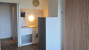 A compact kitchen with a built-in washing machine, a coffee maker, and a clock on the wall. - Studio with sea view, terrace and shared pool (Sainte-Maxime)