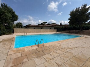 A rectangular swimming pool with two ladders on one side, surrounded by a tiled deck. - Studio with sea view, terrace and shared pool (Sainte-Maxime)