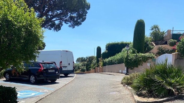A parking area with a white van and a black car, surrounded by greenery and a clear sky. - Studio with sea view, terrace and shared pool (Sainte-Maxime)