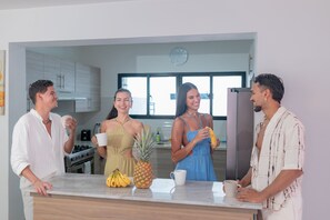 Een moderne keuken met een marmeren aanrecht, een klok aan de muur en een raam dat natuurlijk licht binnenlaat.