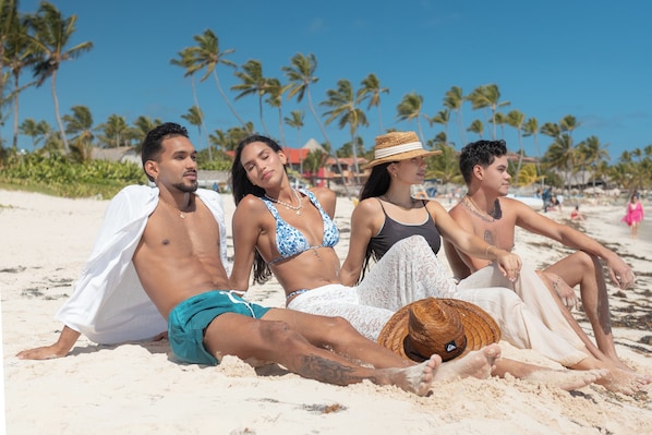 Eine Strandansicht mit Palmen und Menschen, die am Sand entspannen.