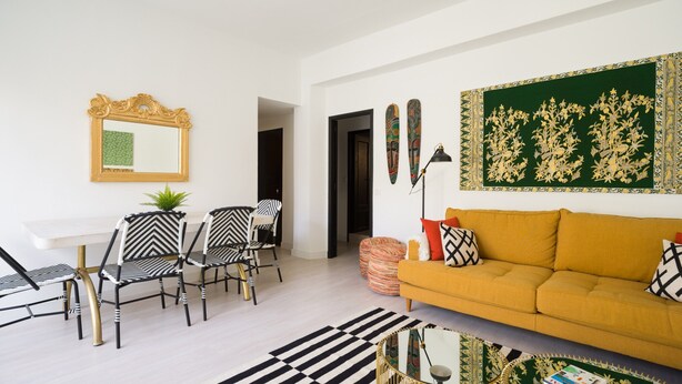 A living room with a sofa, chairs, a coffee table, a patterned rug, and a wall with decorative tapestries. - Townhouse in Las Palmas Near Playa Alcaravaneras (Las Palmas de Gran Canaria)