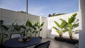 A patio area with a round table, chairs, potted plants, and a white fence. - Townhouse in Las Palmas Near Playa Alcaravaneras (Las Palmas de Gran Canaria)