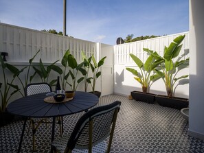 A patio area with a round table, chairs, potted plants, and a white fence. - Townhouse in Las Palmas Near Playa Alcaravaneras (Las Palmas de Gran Canaria)