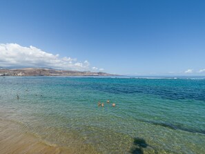 A beach with clear water and a distant view of hills. - Townhouse in Las Palmas Near Playa Alcaravaneras (Las Palmas de Gran Canaria)