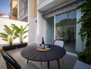 A round table with chairs, a bottle of wine, and potted plants in an outdoor patio area with a tiled floor. - Townhouse in Las Palmas Near Playa Alcaravaneras (Las Palmas de Gran Canaria)