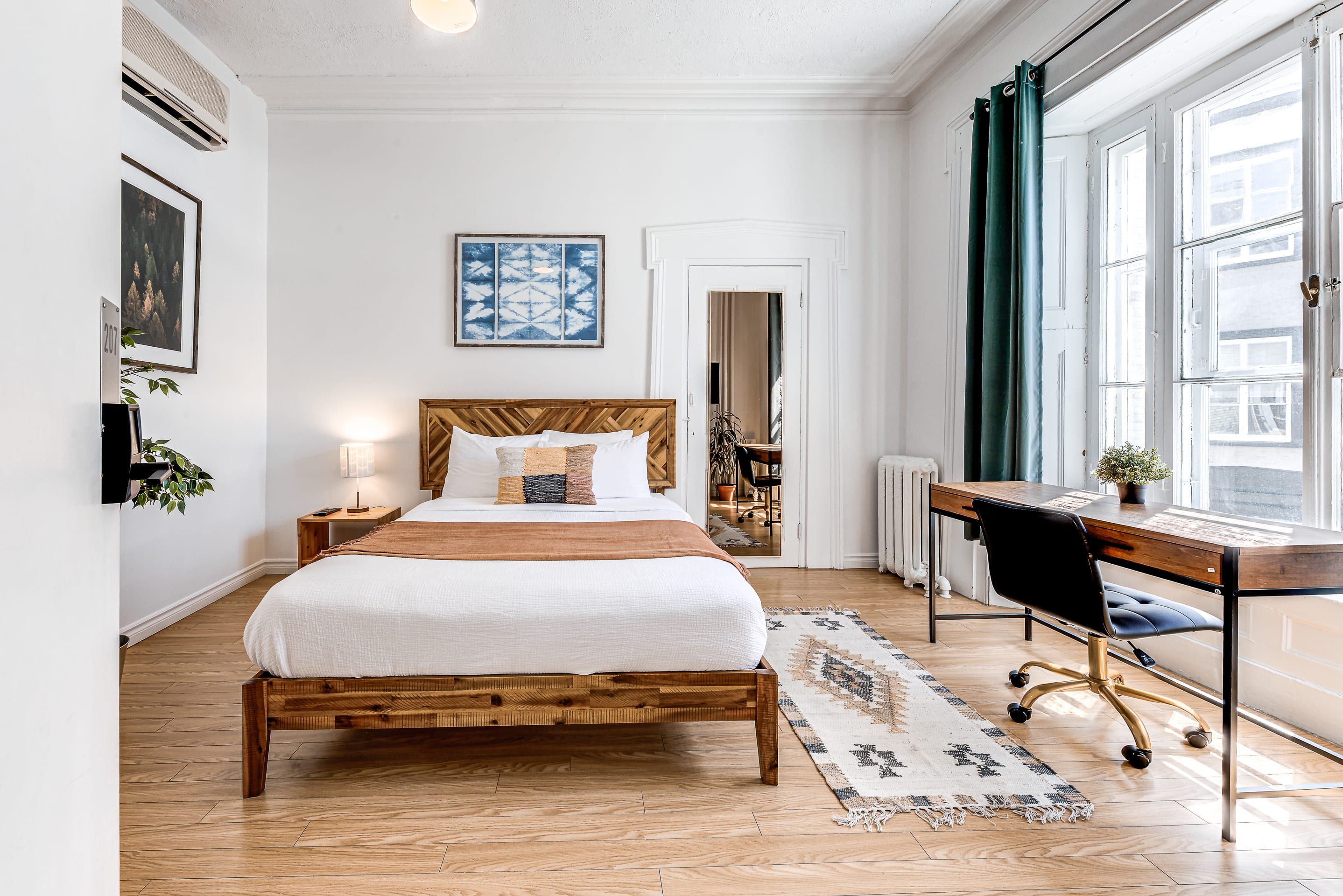 Ein Schlafzimmer mit einem hölzernen Bett, einem Schreibtisch und einem großen Fenster.