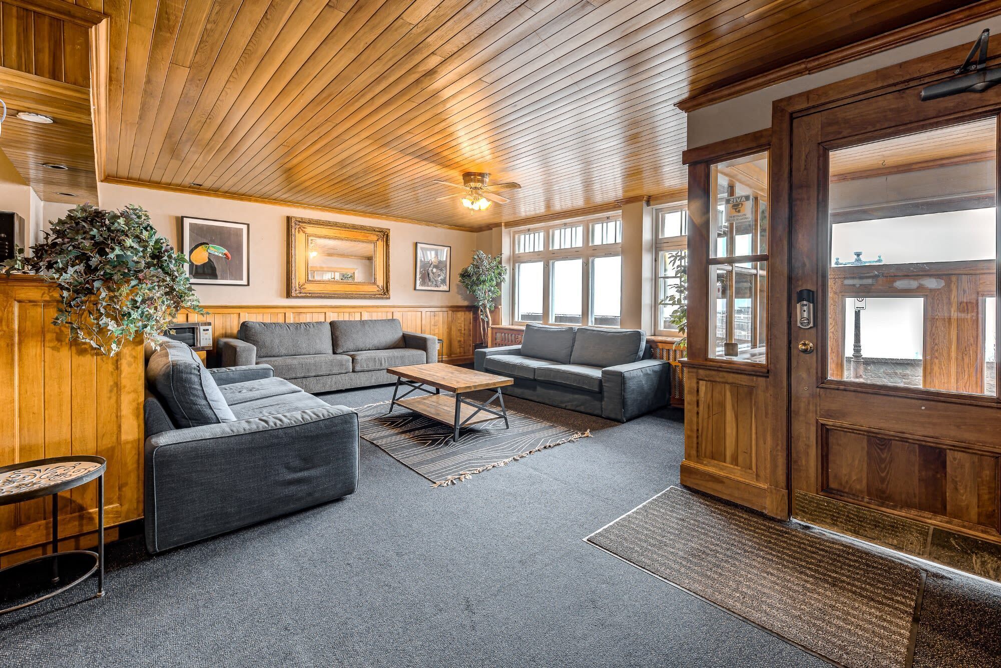A cozy lobby with wooden paneling, a large wooden door, and a seating area with sofas and a coffee table.