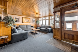 A cozy lobby with wooden paneling, a wooden door, and a seating area with sofas and a coffee table.