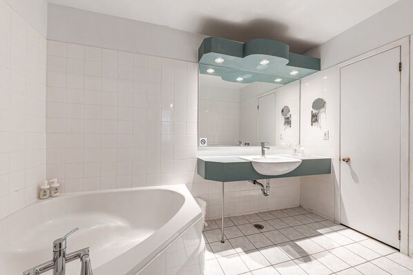 A modern bathroom with a freestanding bathtub, a vanity with a sink, and a mirror with decorative elements.