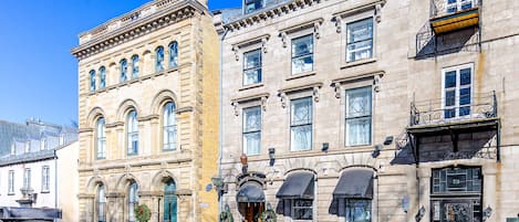Un edificio histórico con varios pisos, ventanas amplias y una entrada destacada con un letrero.