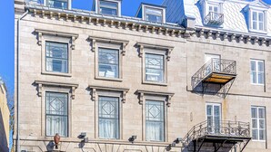 A historic building with a classic facade, multiple windows, and a prominent entrance with a wooden door. - Auberge in Old Quebec -2 bed suite (Québec)