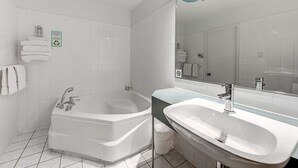A modern bathroom with a freestanding bathtub, a sink, and a mirror. - Auberge in Old Quebec -2 bed suite (Québec)