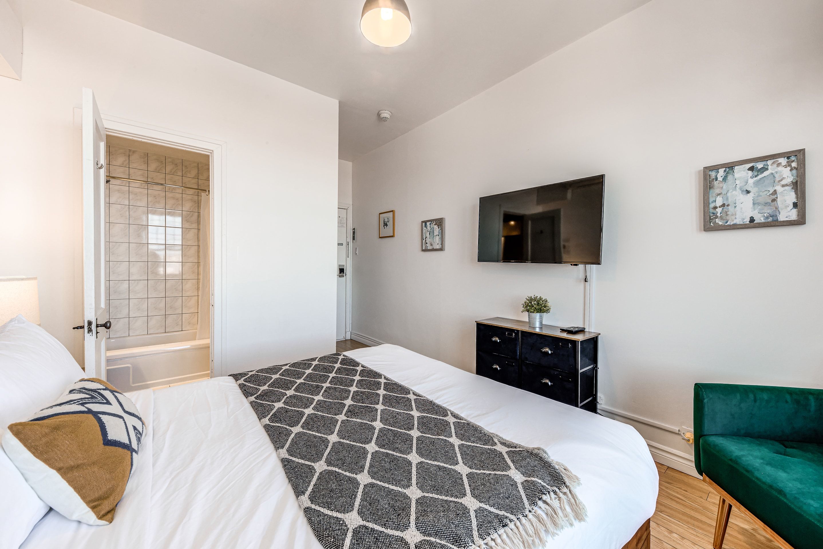 Ein Schlafzimmer mit einem Bett, einem Schminktisch, einem Fernseher und einem grünen Sessel.