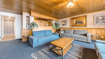 Ett mysigt vardagsrum med en blå soffa, en grå soffa, ett soffbord i trä och en mönstrad matta.