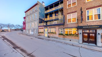 En gatubild som visar en rad högre byggnader med olika arkitektoniska stilar, inklusive fasader i tegel och balkonger.