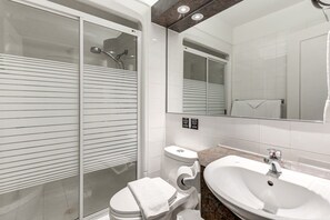 A modern bathroom with a glass-enclosed shower, a white toilet, a sink, and a large mirror. - Auberge in Old Quebec - 1 bed suite (Québec)