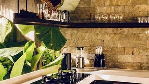 Une cuisine avec un mur en pierre, une cuisinière à gaz et un luminaire suspendu.