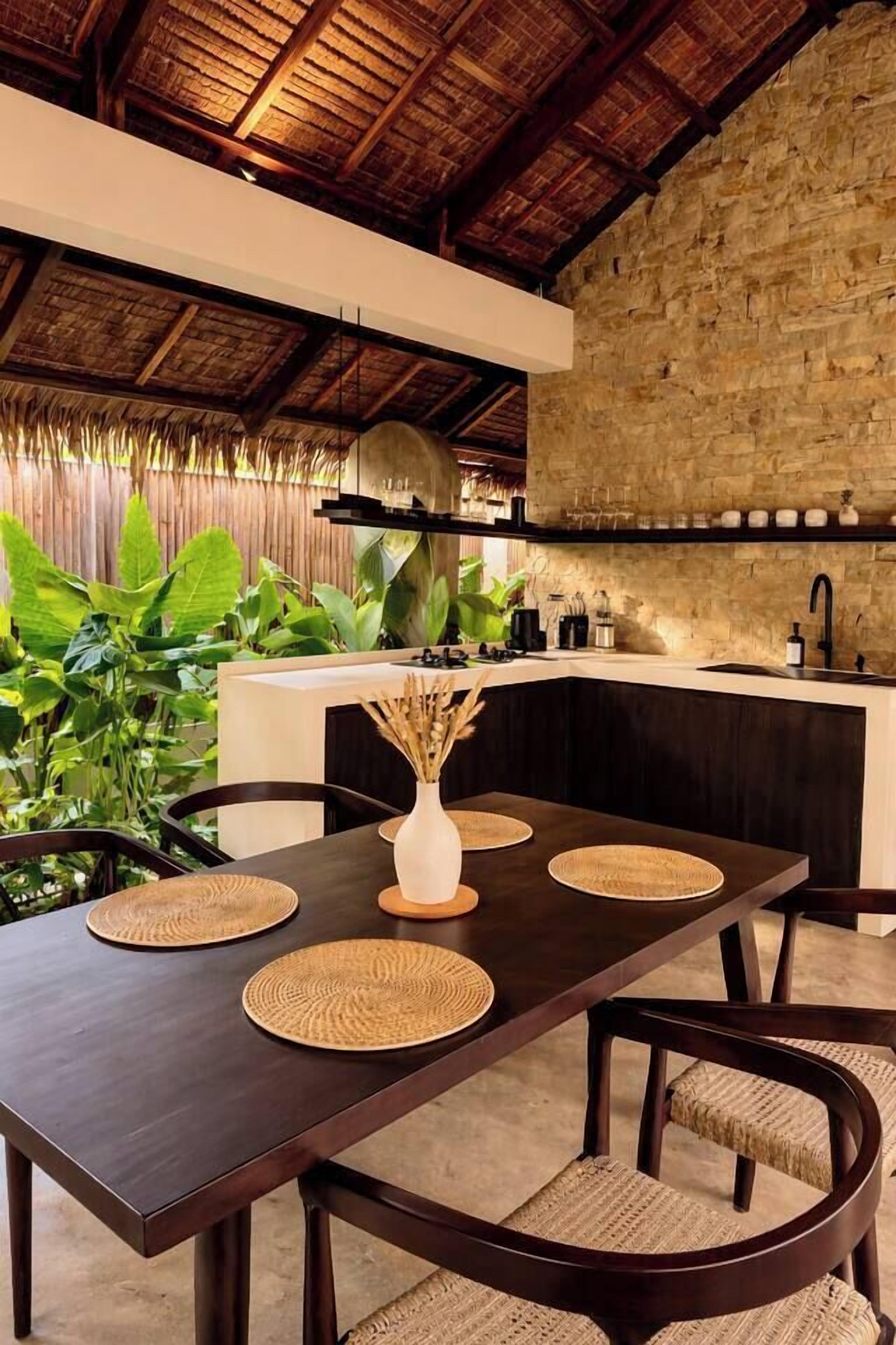 A dining area with a dark wooden table, woven placemats, and wicker chairs.
