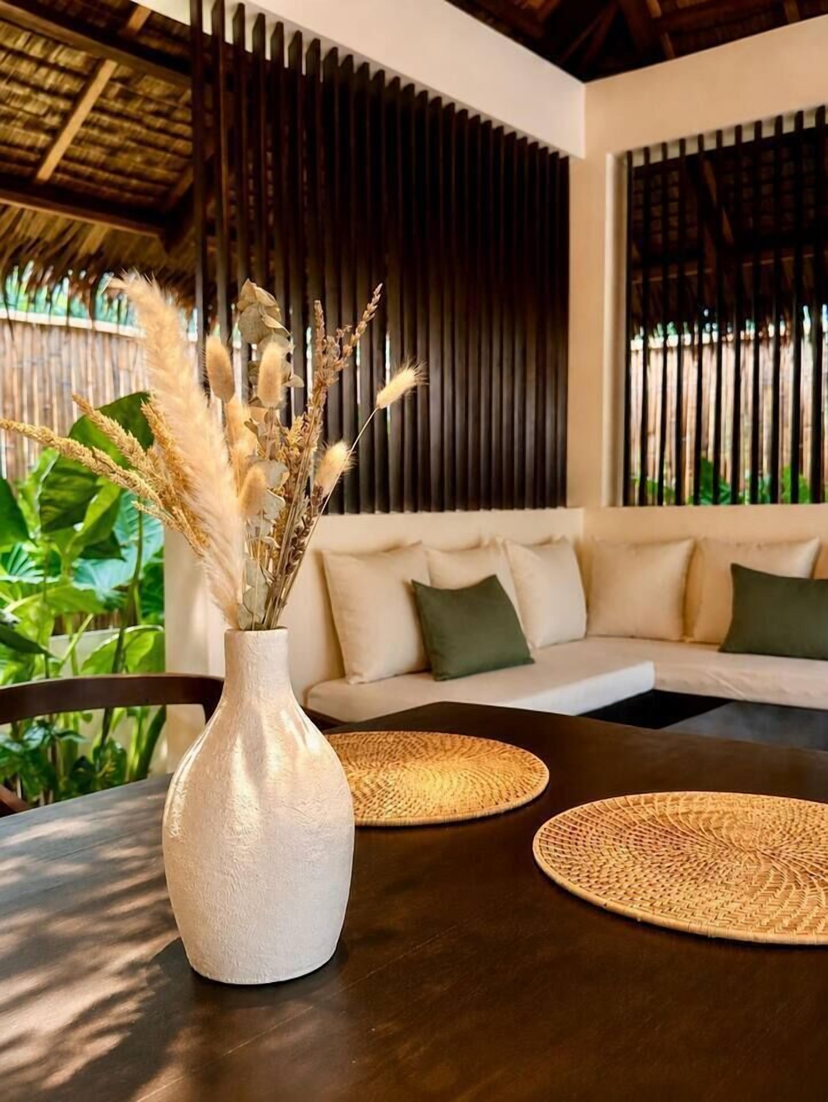 A modern interior with a sofa, a round table, and a vase with dried plants.