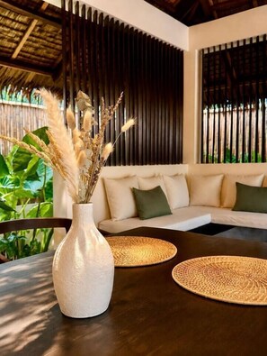 A modern interior with a sofa, a round table, and a vase with dried plants.