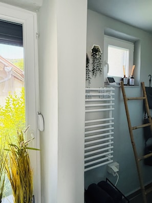 A room with a window, a radiator, a ladder, and a plant.