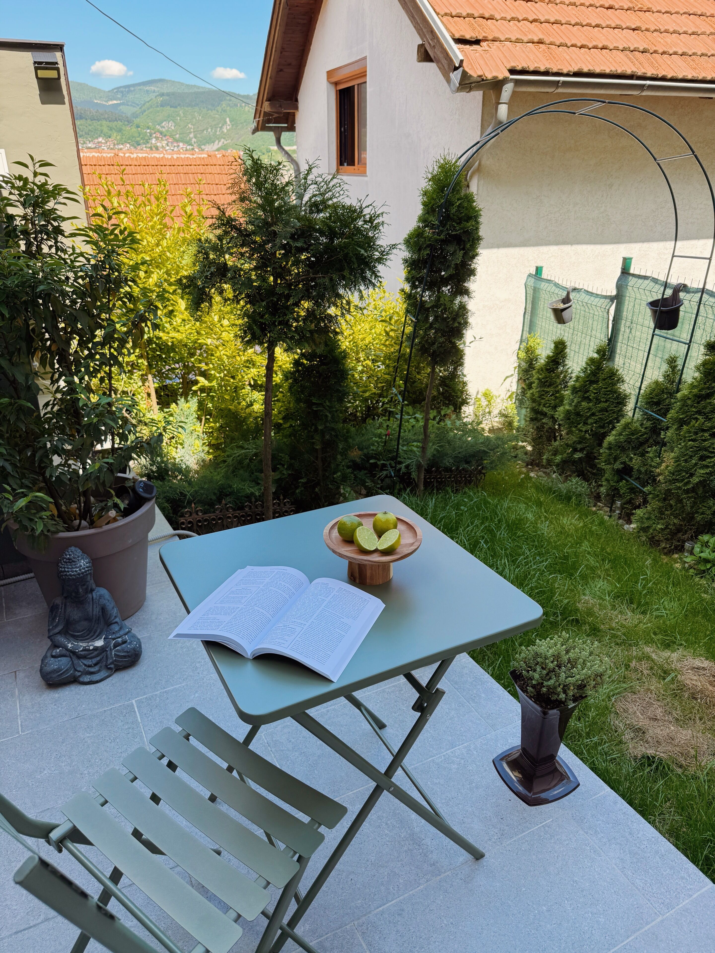 A patio with a table, a Buddha statue, and a book.